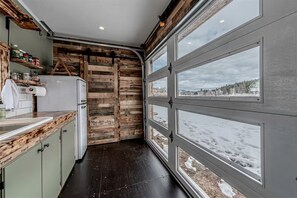 A kitchen with a wooden accent wall, a white refrigerator, and a window with a snowy view.