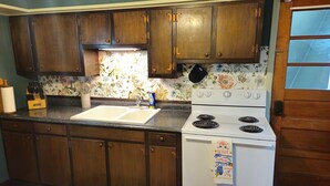 A kitchen with wooden cabinets, a white stove, and a floral backsplash. -  The Coal Breaker at The Ferndale Inn. 1225 W Fern St Coaltownship Pa 17866. (Fairview-Ferndale)