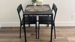 Taula de dinar amb quatre cadires, una planta en test i un objecte decoratiu a la taula.