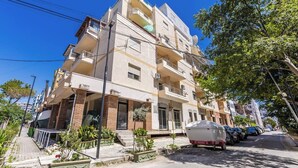 Un immeuble résidentiel à plusieurs étages, doté de balcons, d’un espace extérieur couvert et d’un bateau garé.