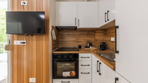 Une cuisine compacte équipée d’un four encastré, d’une plaque de cuisson et d’une machine à café.