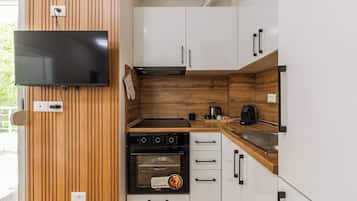 Et lille køkken med indbygget ovn, komfur og kaffemaskine.