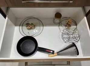 A kitchen with a stove, a frying pan, and a grater.