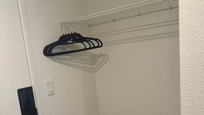 Un placard d’angle avec une étagère en métal et une tringle pour suspendre les vêtements.