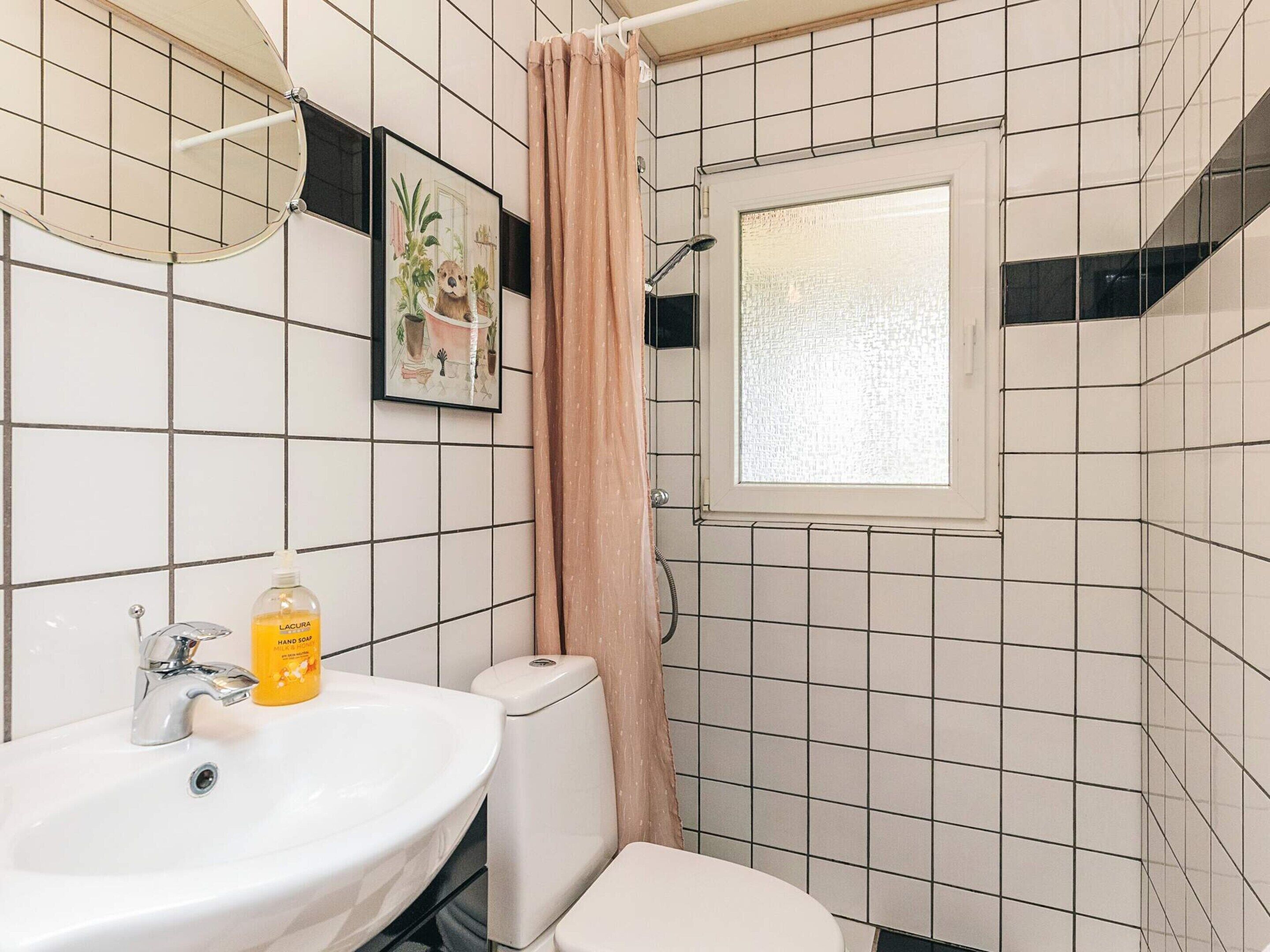 A bathroom with a sink, toilet, and a window.