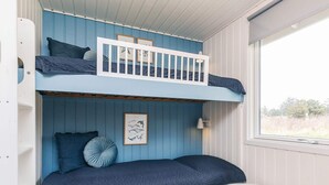 A bunk bed room with a white railing, a framed picture on the wall, and a small white table. - 6 Person Holiday Home in Lokken (Lokken)