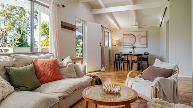 Un salon comprenant un canapé, des fauteuils, une table ronde et un coin repas avec des chaises.