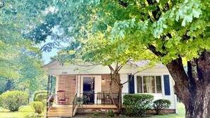 A house with a brick exterior, a porch with a red chair, and a tree in front. - Beautiful modern renovated 4 bedroom and 4.5 bath within a block of HPU (High Point)