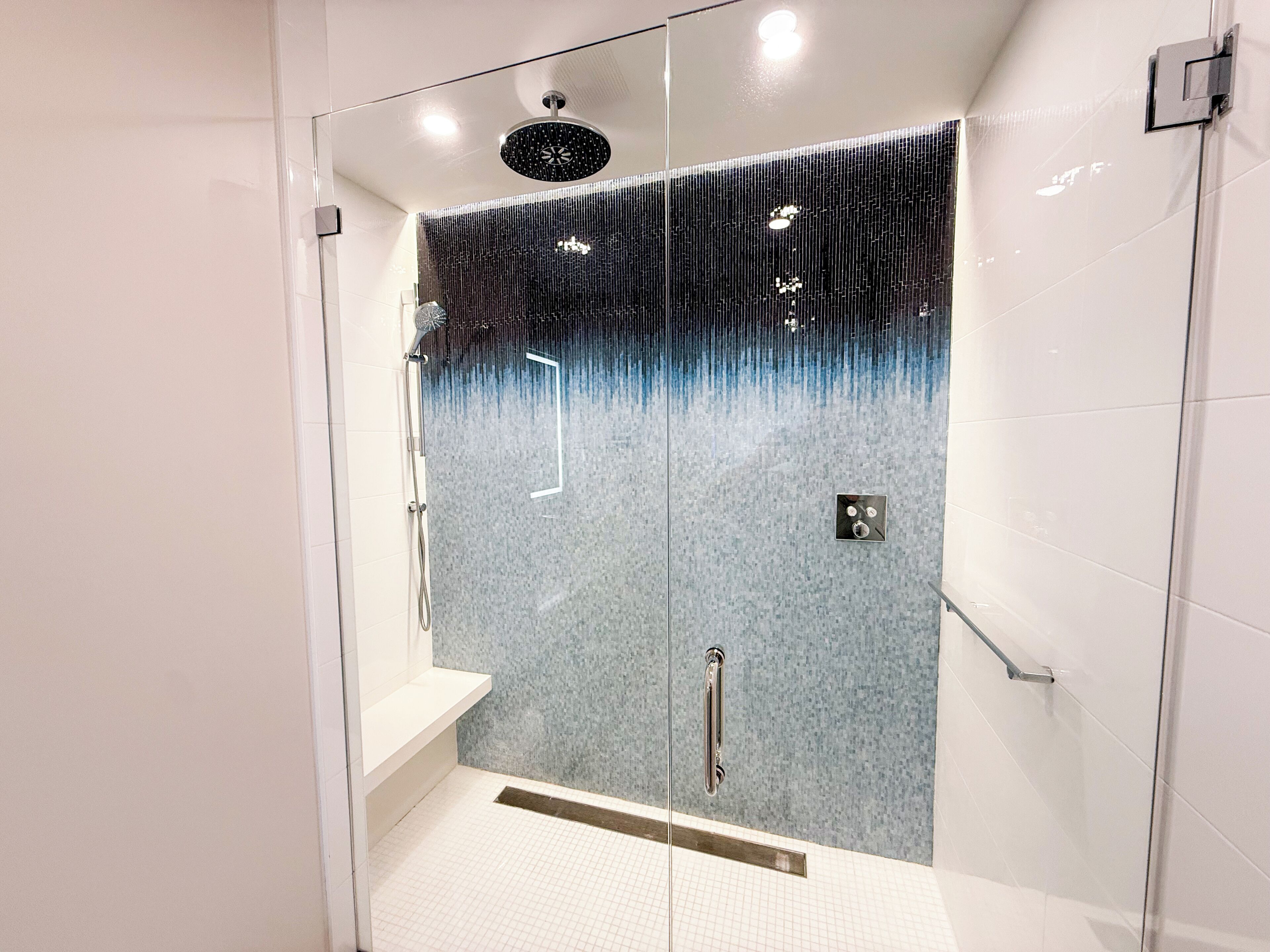 Una ducha moderna con función de lluvia, panel de control y puerta de cristal.
