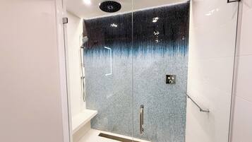 Una ducha moderna con función de lluvia, panel de control y puerta de cristal.