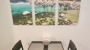 Une table à manger avec des chaises, un set de table et un saladier rempli de fruits.