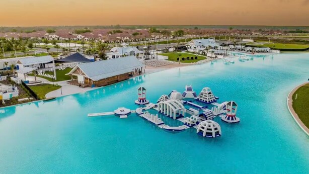 Ein Resort mit großem Schwimmbecken, mehreren Wasserrutschen und einem Yachthafen mit Booten.