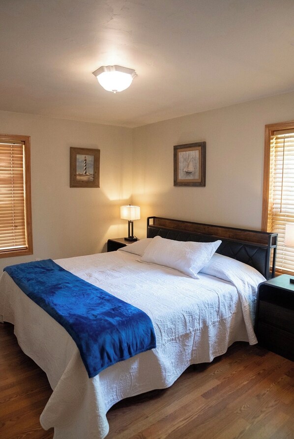 A neatly made bed with a blue and white bedspread, two bedside tables with lamps, and framed pictures on the walls.