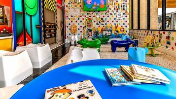A children's play area with colorful furniture and a large TV screen.