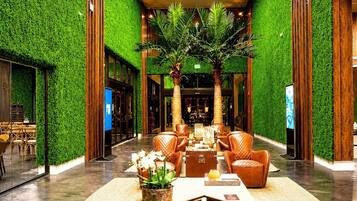 A lobby with a green wall, a reception desk, and a seating area with chairs and a table.