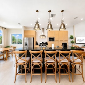 Een moderne keuken met een centraal eiland, houten stoelen en hanglampen.