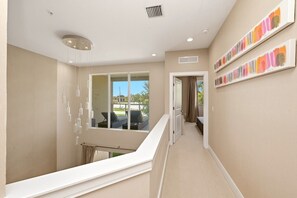 A hallway with a staircase, a window with a view, and a door leading to a room. - LuxuryResort~MagicVillage~Ensuite Baths~NearDisney (Kissimmee)