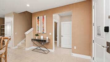 A hallway with beige walls, white doors, a staircase, and a metal-framed table with a plant.