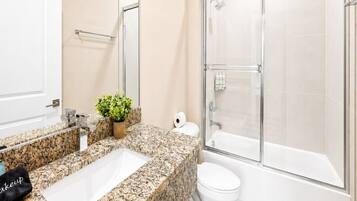 Full bathroom with granite vanity, glass-enclosed shower, soaking tub, and bright natural light