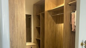 A wooden walk-in closet with open shelves, a small countertop, and a door with a brass handle. - Modern 2-bedroom Apt | Dreamland Golf & Pool View (Giza Governorate)