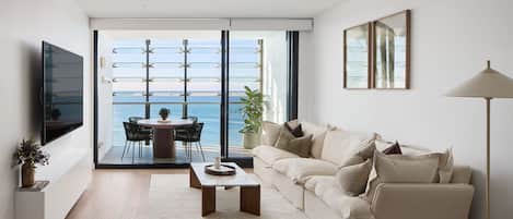 A modern living room with a balcony, a flat-screen TV, a sofa, and a dining table.