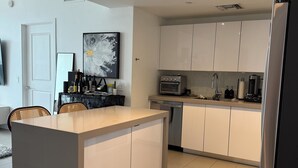 Una cucina moderna con mobili bianchi, un'isola centrale, un frigorifero e un forno a microonde.