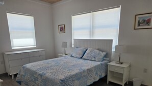 Ein Schlafzimmer mit einem Bett, zwei Nachttischen, einem Fenster und einer Heizung.