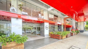 En modern byggnad med en glasfasad, uteservering och planteringar.