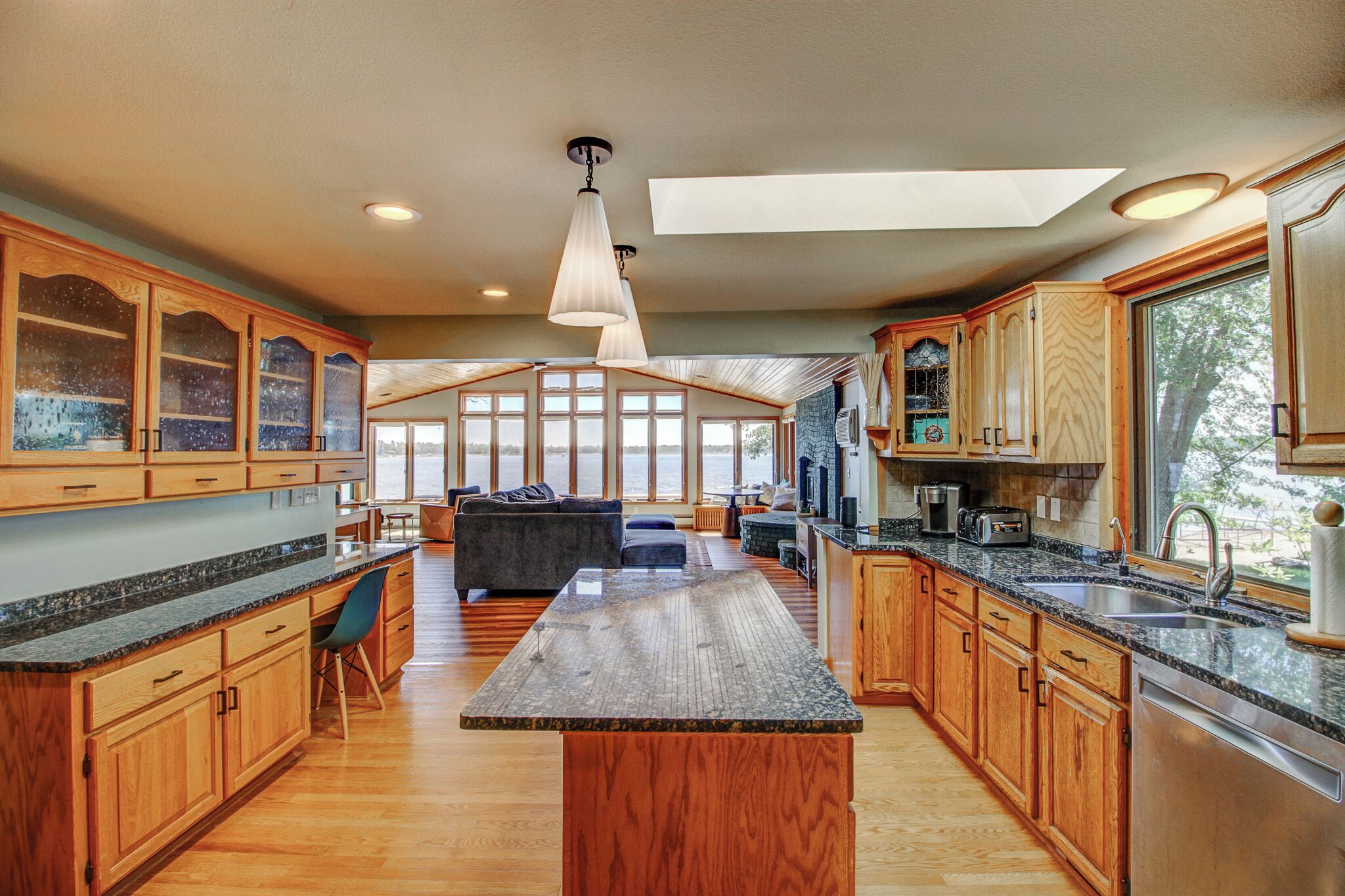 A spacious kitchen with wooden cabinets, granite countertops, and a central island.
