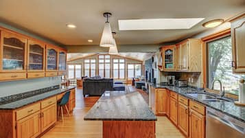 A spacious kitchen with wooden cabinets, granite countertops, and a central island.