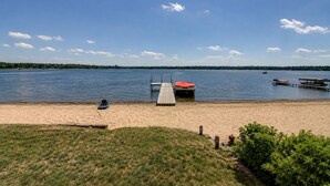Ein See mit einem Strand, einer Anlegestelle, einem Boot und einem Jetski.