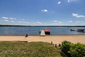 A lakeside beach with a dock, a boat, and a jet ski.