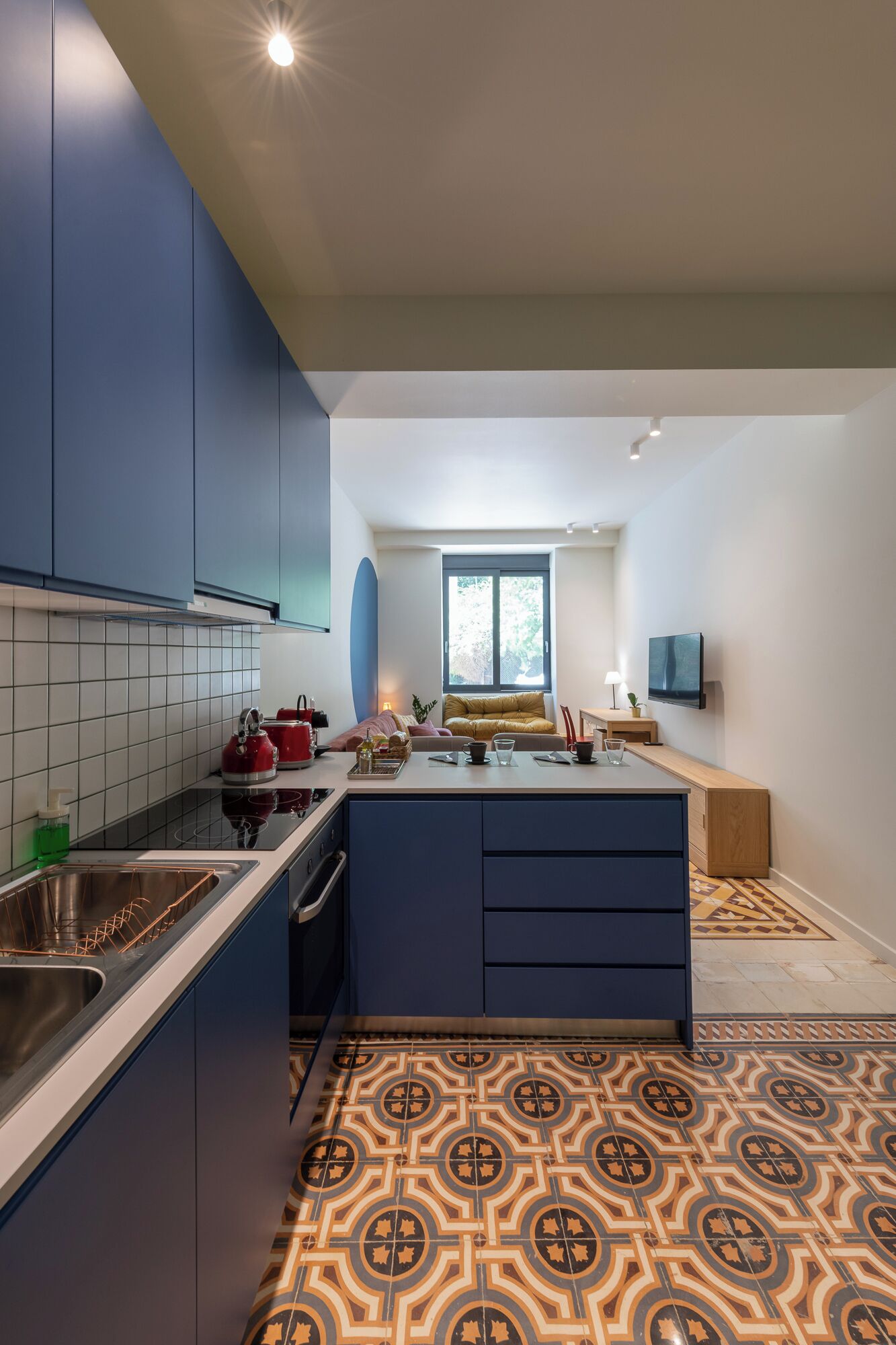 Cozinha moderna com armários azuis, piso estampado e uma ilha central.