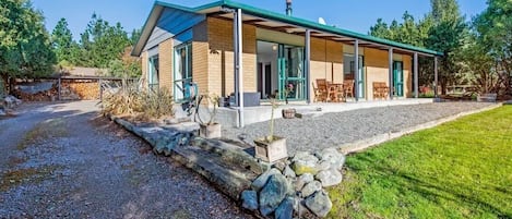 A modern house with a covered porch, a gravel driveway, and a stone retaining wall.