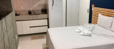 Une chambre d’hôtel équipée d’un lit, d’une petite kitchenette, d’un réfrigérateur et d’une porte avec une pancarte.