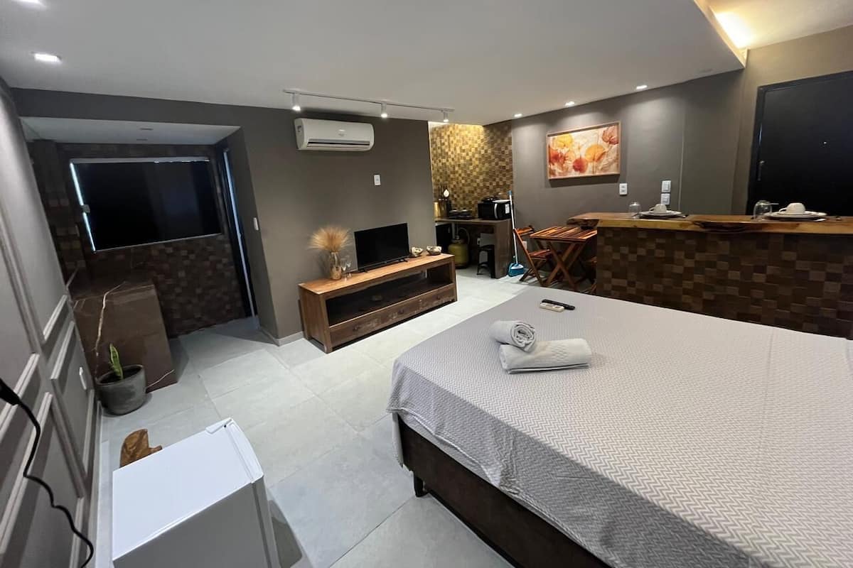Una habitación de hotel moderna con una cama grande, un televisor, un escritorio y un área de descanso.