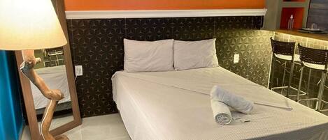 Ein Hotelzimmer mit Bett, Spiegel, Lampe und Stuhl.