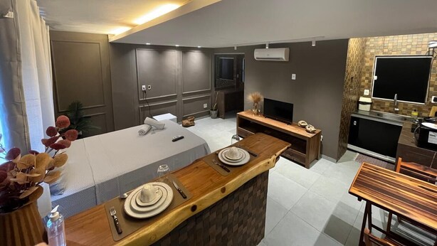 A modern kitchen with a central island, a dining area, and a living space with a TV.