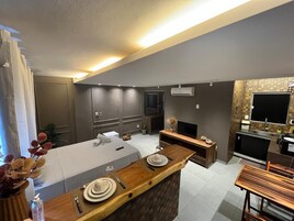 Uma cozinha moderna com uma ilha central, uma área de jantar e um espaço de estar com televisão.