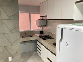 Uma cozinha com fogão a gás, geladeira e janela.