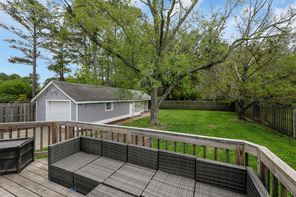 A deck with wicker furniture, a shed, and a fenced yard with trees.