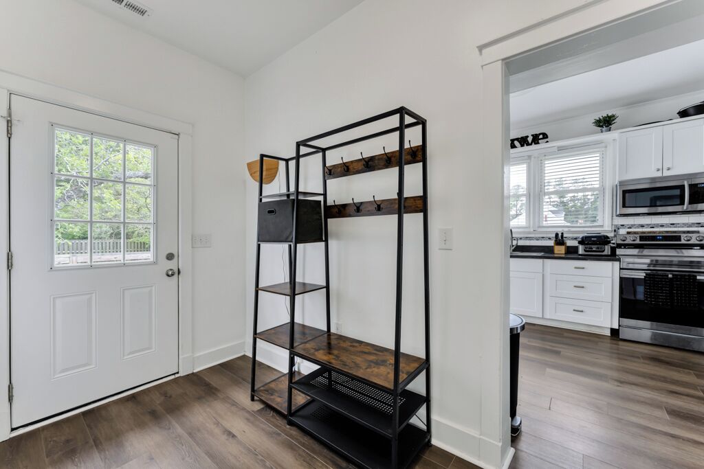 A kitchen with white cabinets, a black metal shelf unit, and a microwave.
