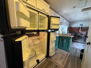 Una cocina compacta con la puerta del refrigerador abierta, un fregadero y gabinetes color turquesa.