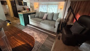 A compact RV interior with a kitchenette, a sofa, a dining table, and a chair. - 2-bedroom RV in fantastic Clearwater with AC and some equipments for fitness (Clearwater)