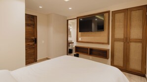 Un dormitorio con cama, televisor montado en la pared, armario de madera y una lámpara en el techo.