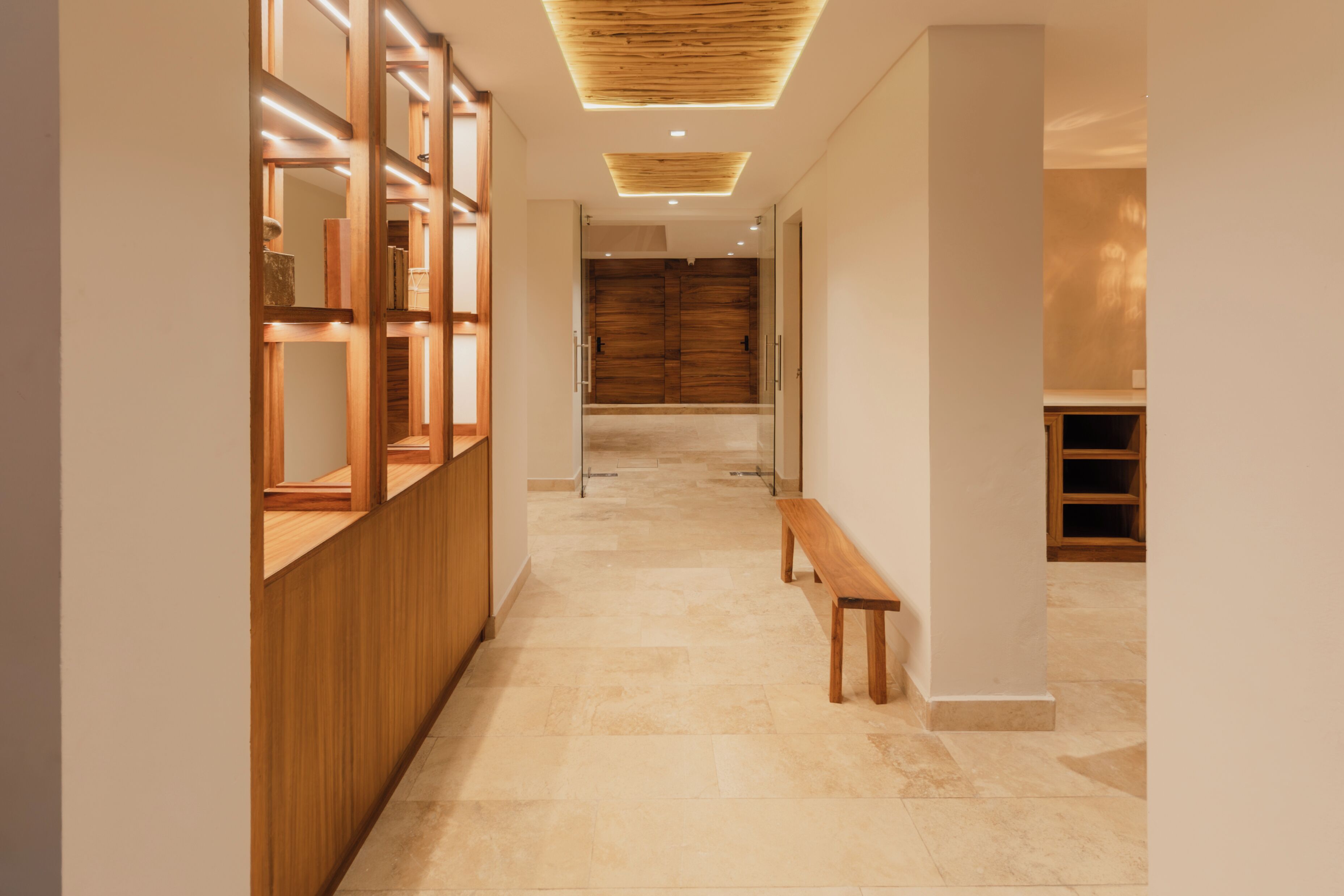 Un pasillo con un banco de madera, un mostrador de recepción de madera y un gran puerta de madera al final.