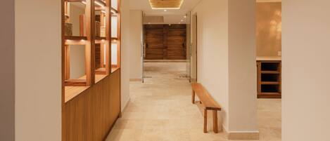Un pasillo con un banco de madera, un mostrador de recepción de madera y un gran puerta de madera al final.