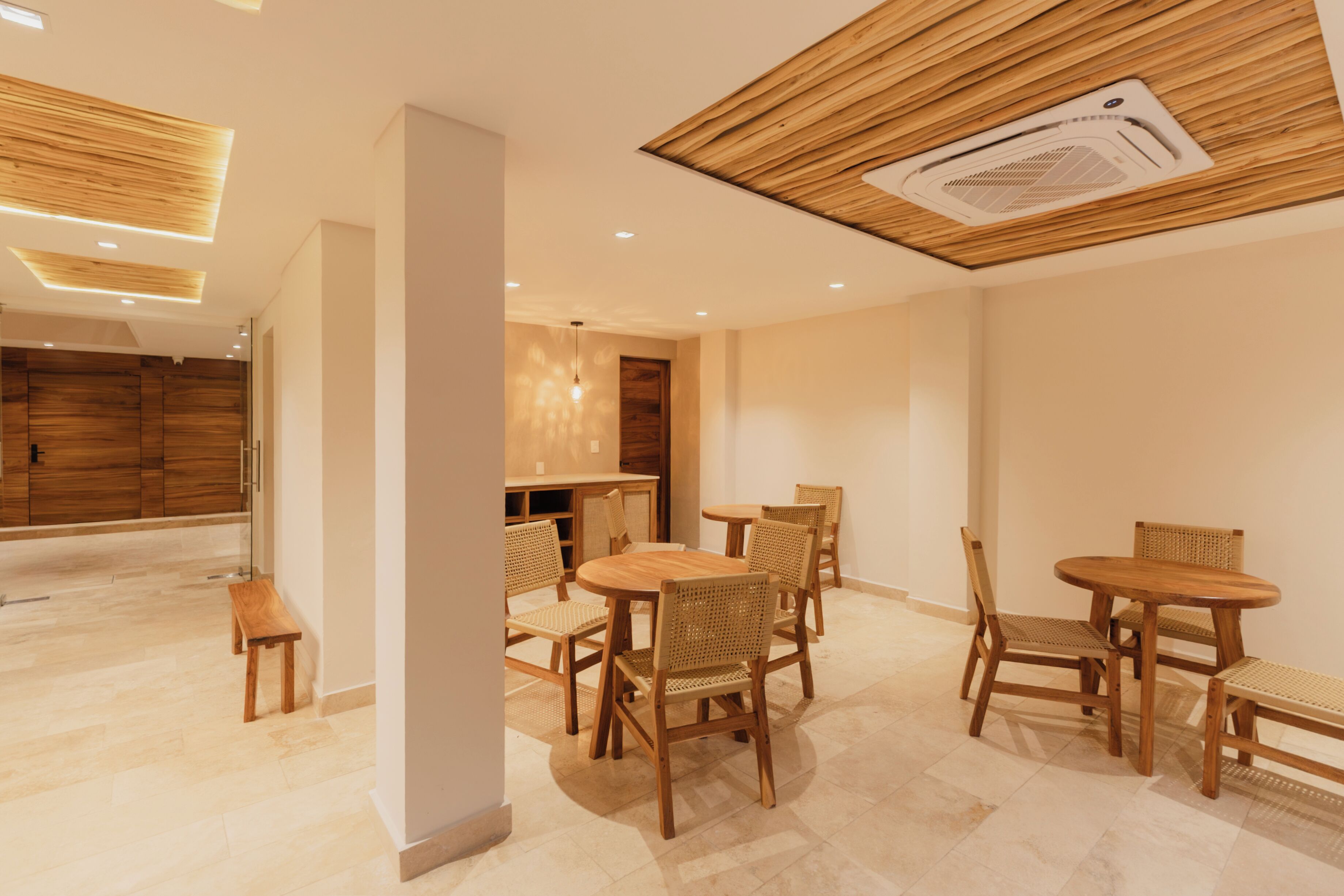 A modern interior with wooden furniture, a ceiling with a built-in air vent, and a hallway leading to a wooden door.