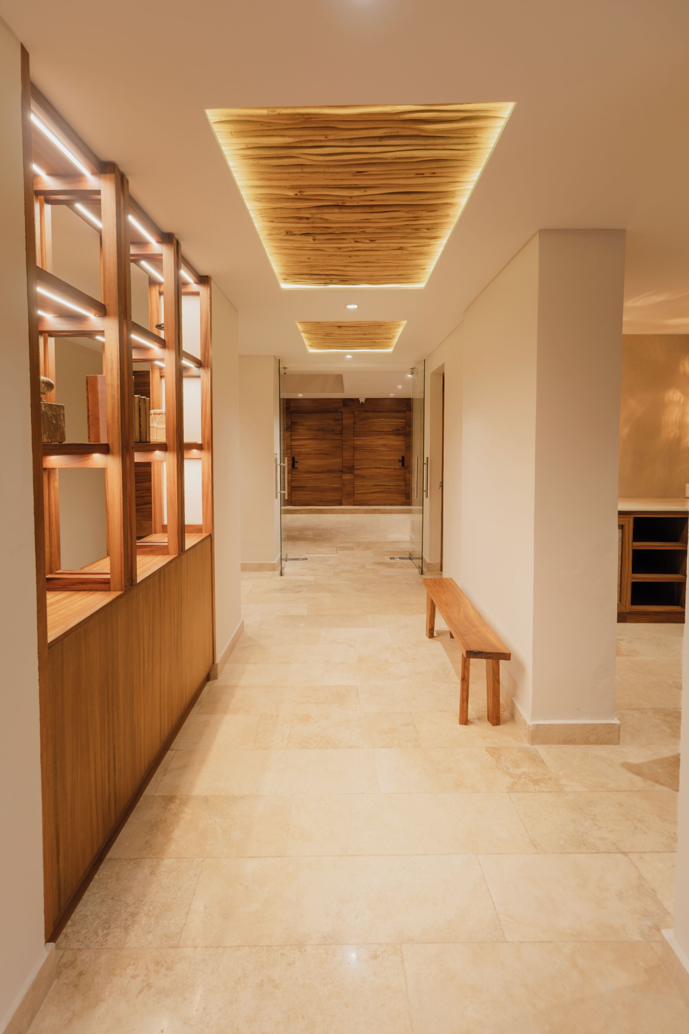 A hallway with a wooden bench, a wooden shelving unit, and a ceiling with a slatted design.