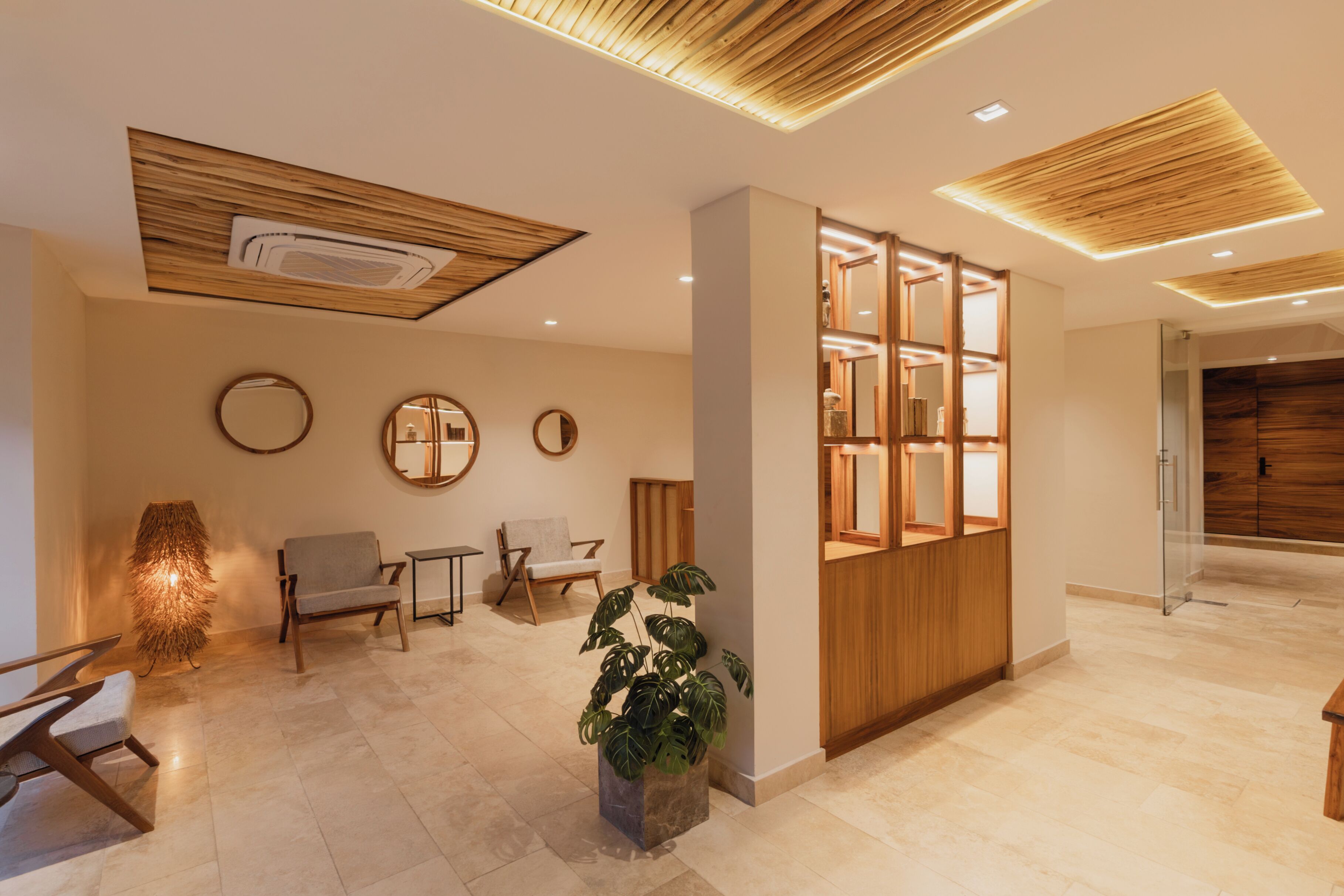 A modern lobby with a reception desk, seating area, and a wooden partition with glass panels.
